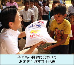 子どもの目線に合わせてお米を手渡す井土代表