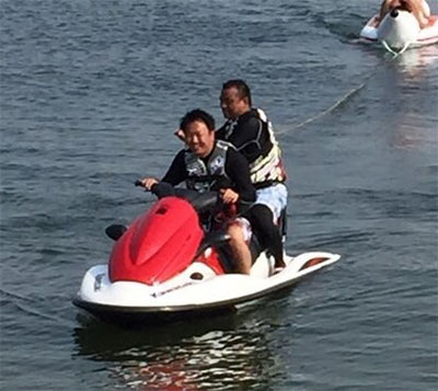 沖縄の海でジェットスキーを楽しむ諸藤壮一氏(前)と岡野勝英氏(後部座席)