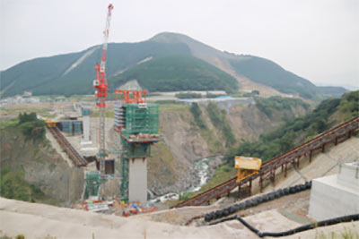24時間体制で復旧工事が進められている阿蘇大橋地区。手前が阿蘇大橋架橋現場、右奥が砂防事業の現場。2台のインクライン(黄色い台車)が稼働するのは、全国的にも珍しい。