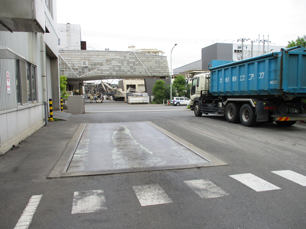 道路左の計測器（トラックスケール）でトラックに積んだ生ごみの重量を測定