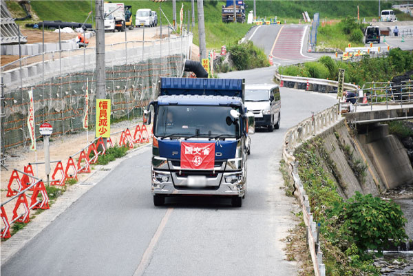 工事車両などが行き来する県道52号線。国交省発注工事のダンプには、住民対策として、フロントにナンバーをつけ、特定しやすいようにしている。