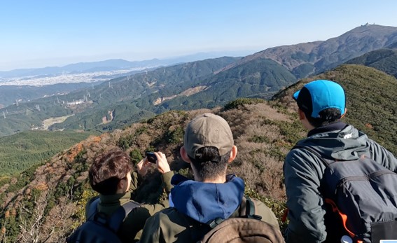 福岡方面の展望を楽しむ学生たち　満足感が溢れている 右上は脊振山（1,055m）