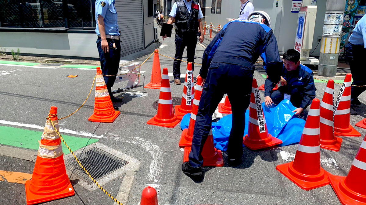 陥没箇所をシートで覆う福岡市職員