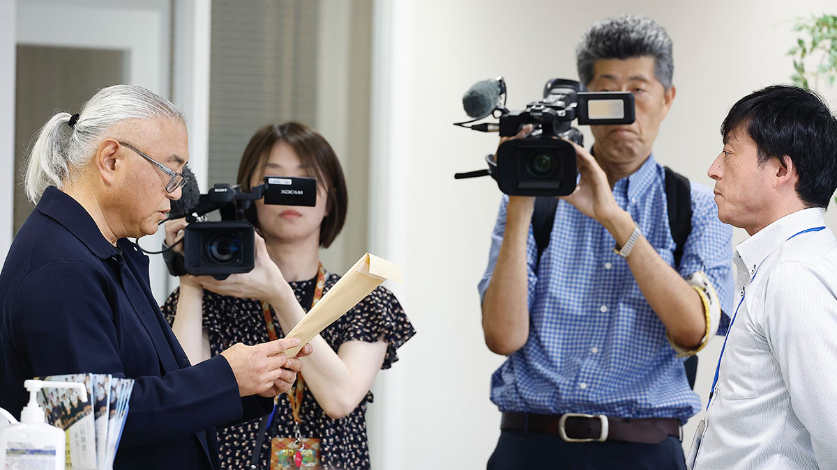 武雄市長あての要望書を読み上げ署名を提出する「武雄の未来を守る会」の野田尚之・代表世話人(左)