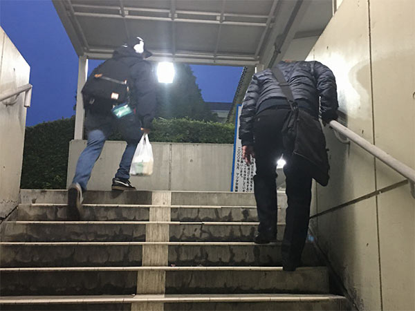 地下道の階段をしんどそうに登る高齢の工員