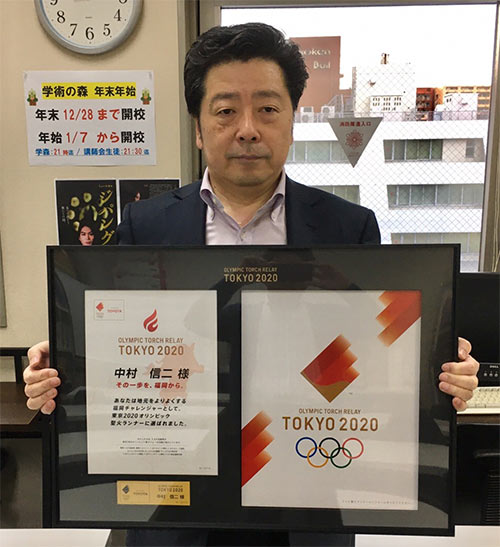 TOKYO2020聖火ランナー認定証と記念のタスキを手にする中村理事長。