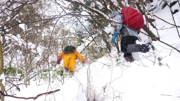 雪深い谷沿いのコースを進む