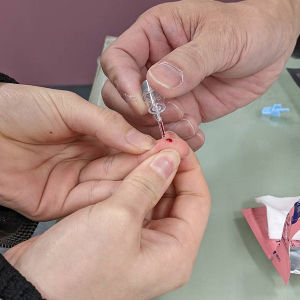 指から血液を採取して薬剤と混ぜて抗体反応を測定する。無痛針を使用するので痛みはない