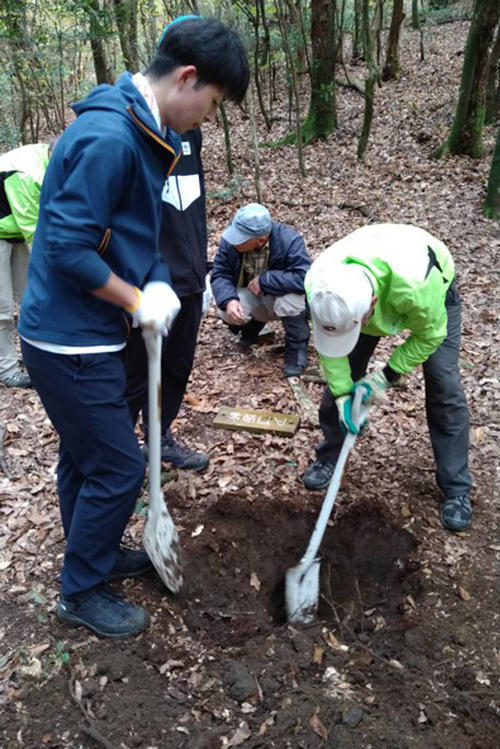 道標設置の穴掘りを手伝う学生のK君（左） 作業に手慣れた副代表T（右）