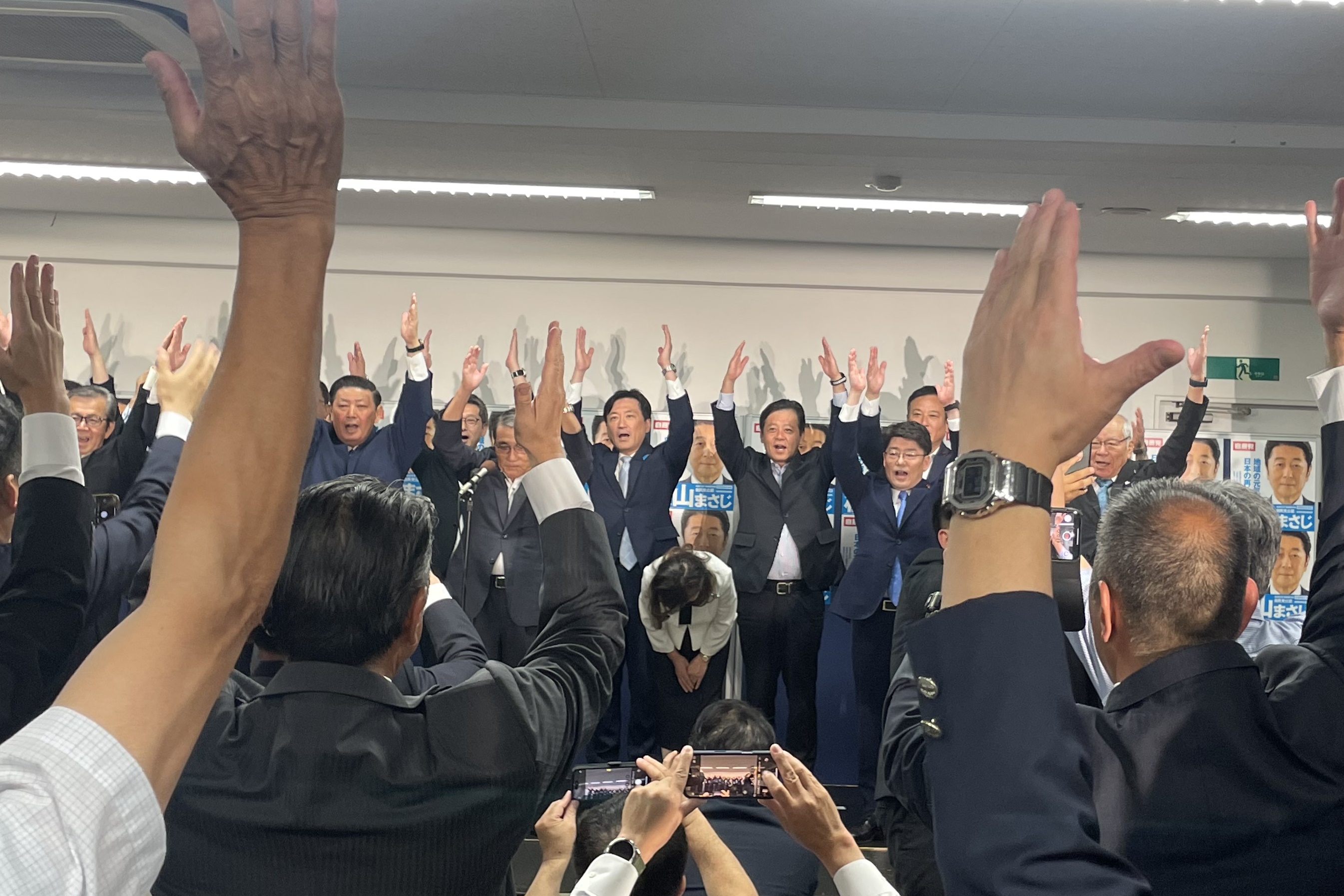 当選確実を受け万歳をする松山氏の選挙事務所に集まった支持者