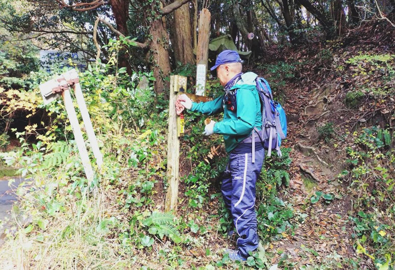 三瀬峠の道標を磨く会員W 左側が国道263号