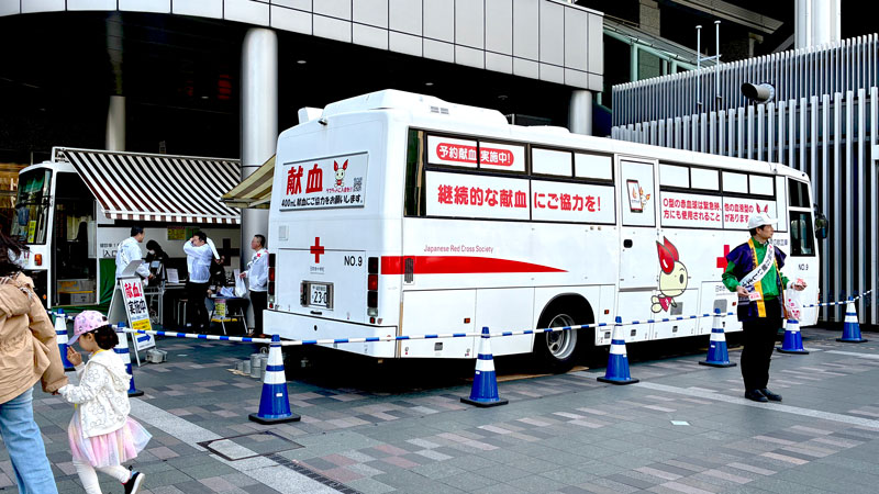献血を呼びかけるライオンズメンバーと献血車