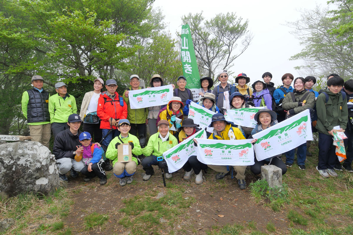 記念タオルを広げて登山者と記念撮影 （緑のジャンパーがスタッフ）