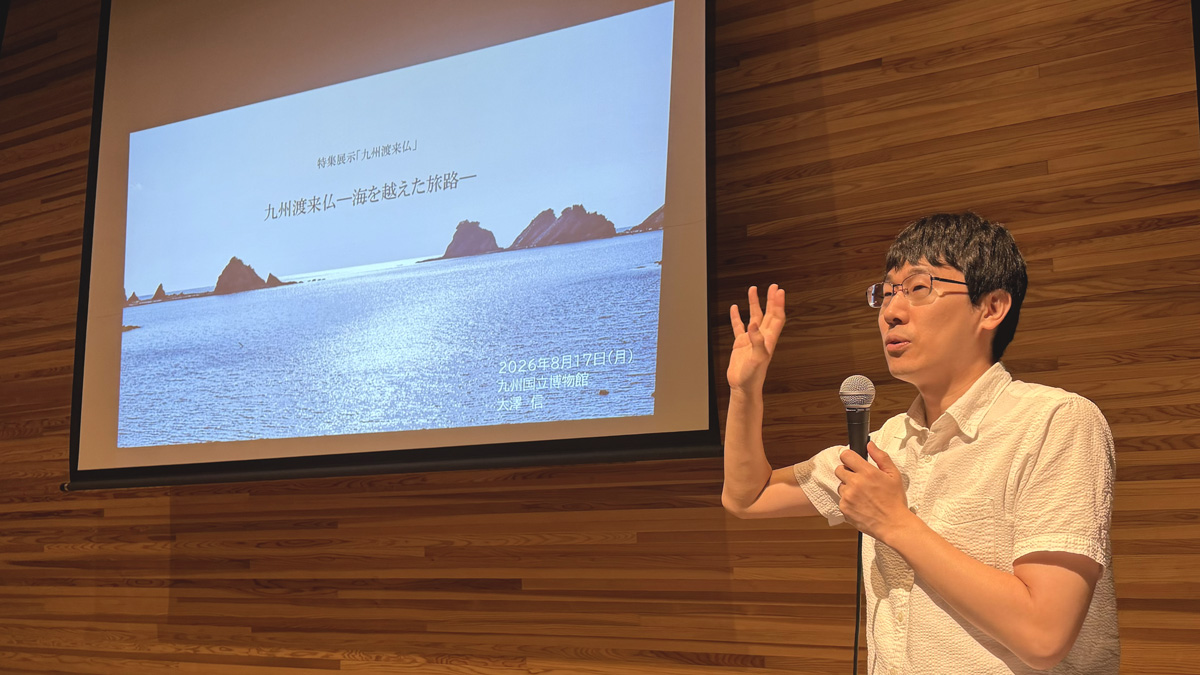 対馬の海を背景にしたスライドの前で、渡来仏への思いを熱く語る大澤信氏